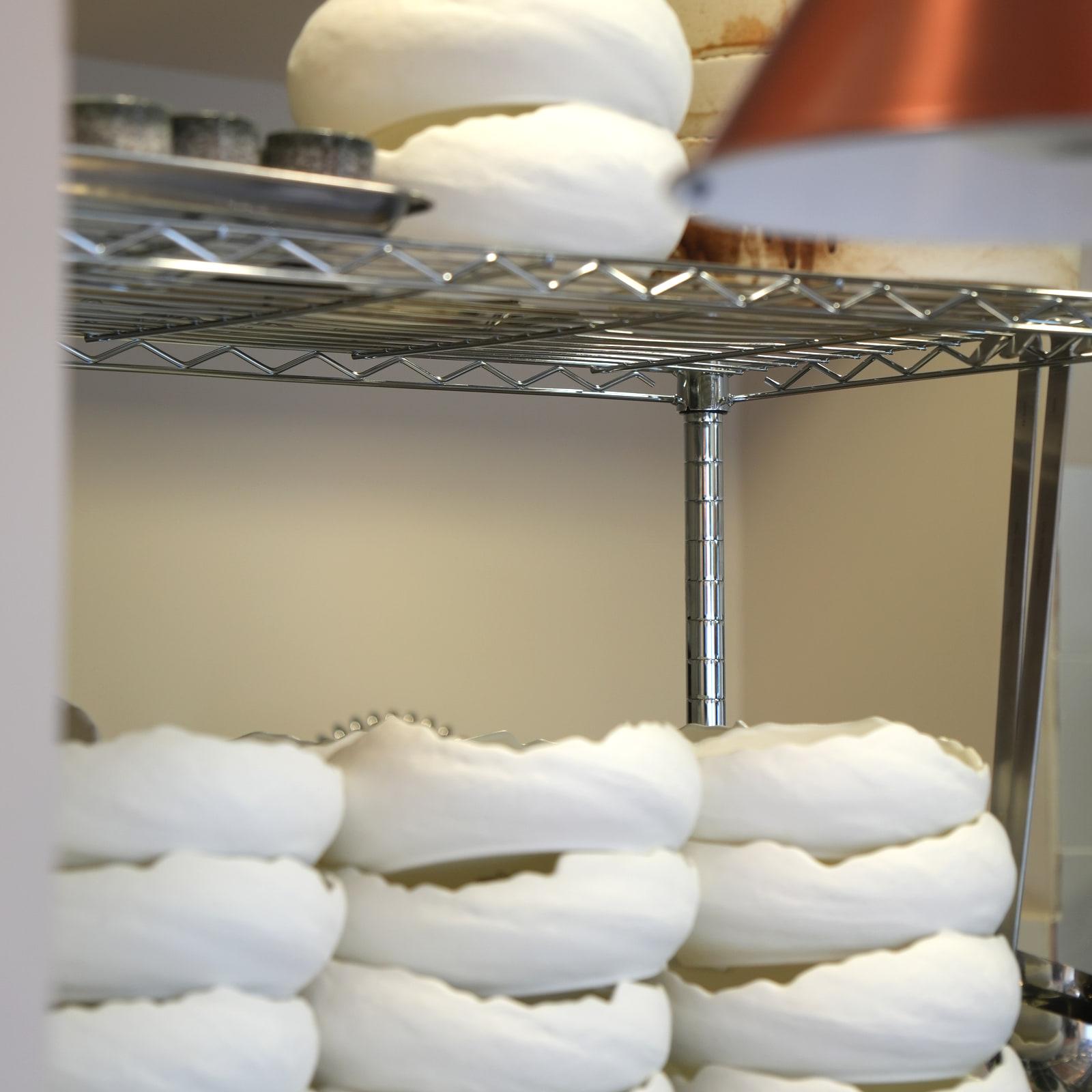 Forme di formaggio fresco nel telo, su uno scaffale della cucina HRANA