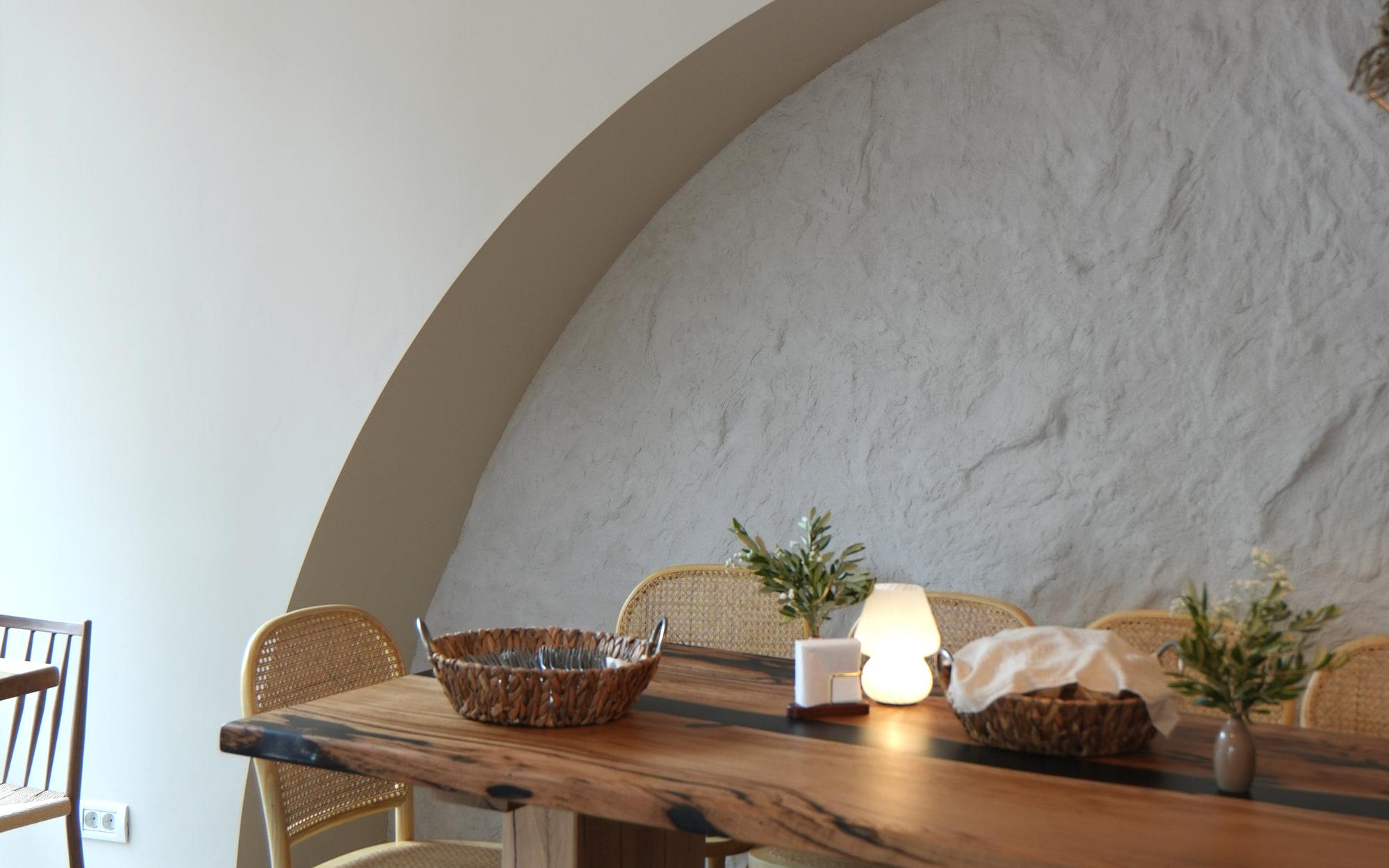 La sala di HRANA, Hunedoara: l'arco bianco, la lampada intrecciata e il lungo tavolo di legno