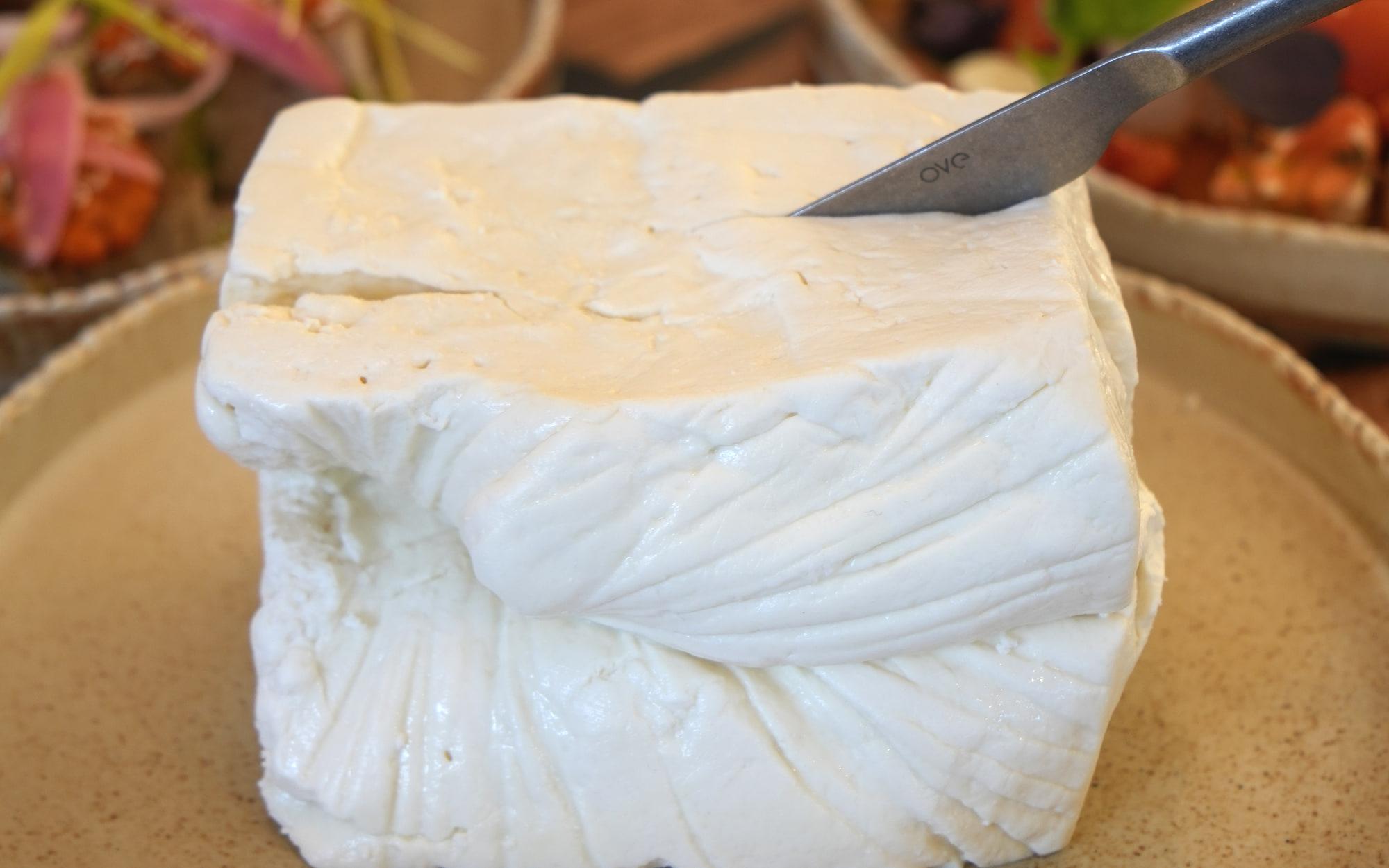 Telemea nel telo su un piatto di ceramica, accanto a ciotole di verdure arrosto, da HRANA
