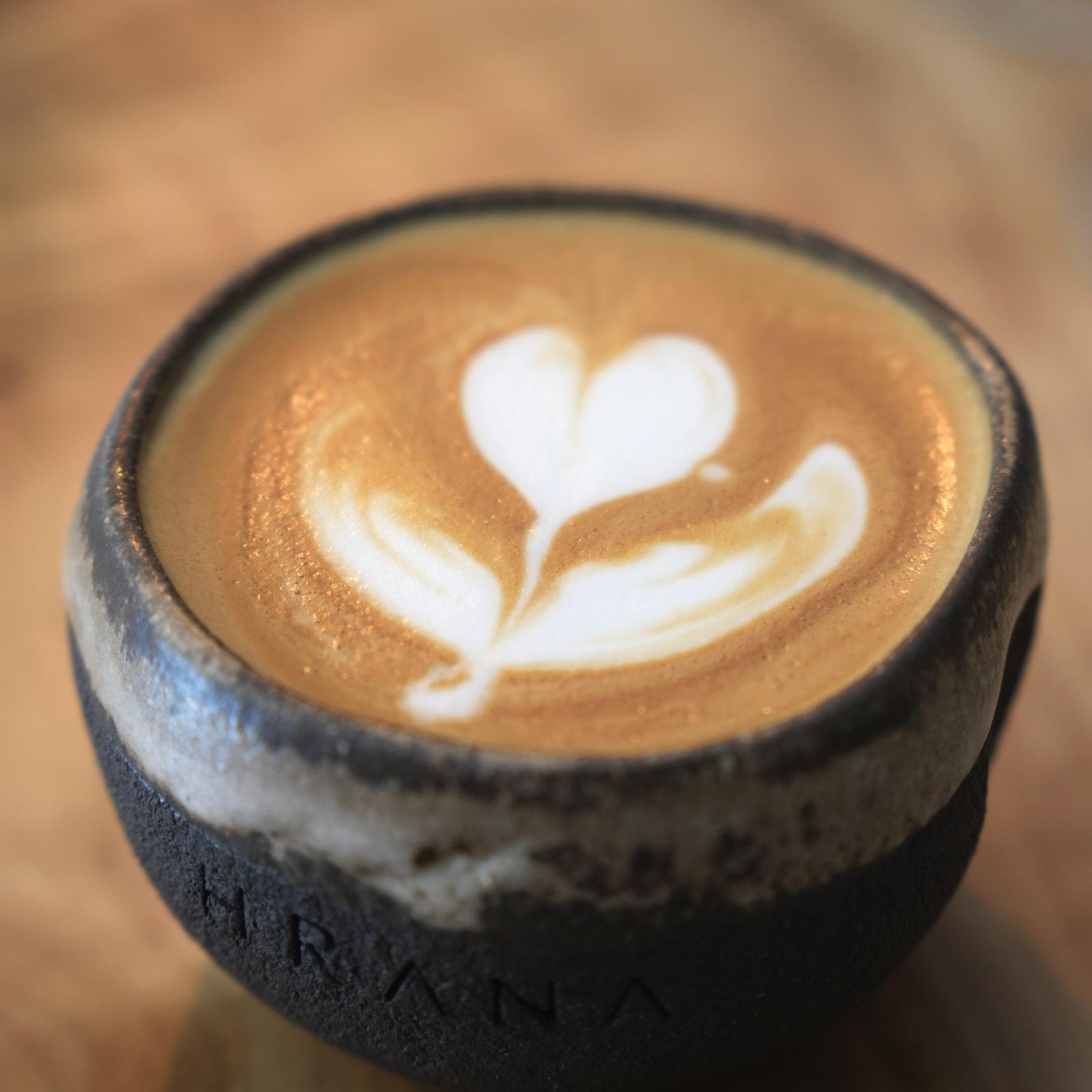 Cappuccino con latte art in una tazza di ceramica HRANA