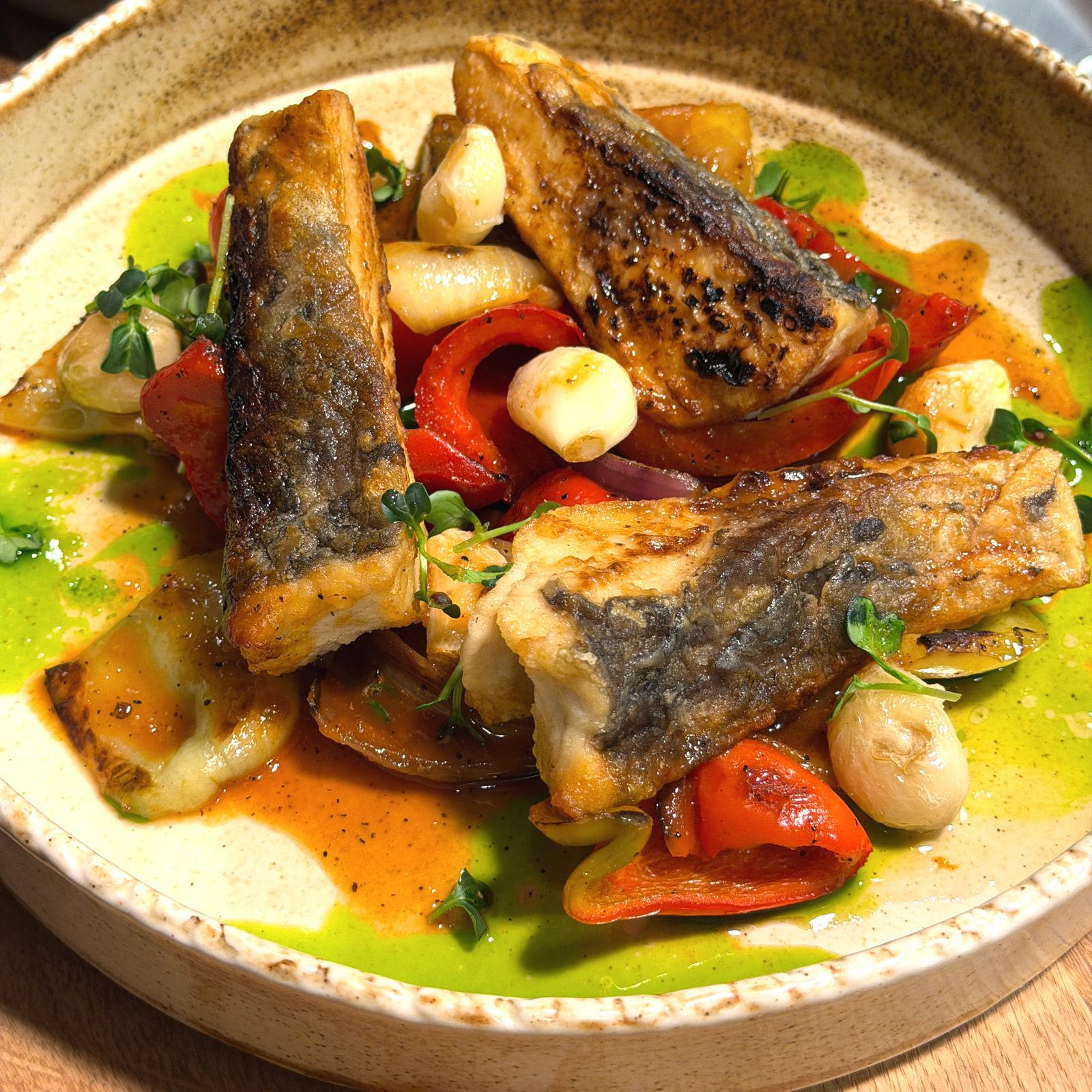 Carpa con verdure arrosto, peperoni e aglio arrosto su un piatto di ceramica